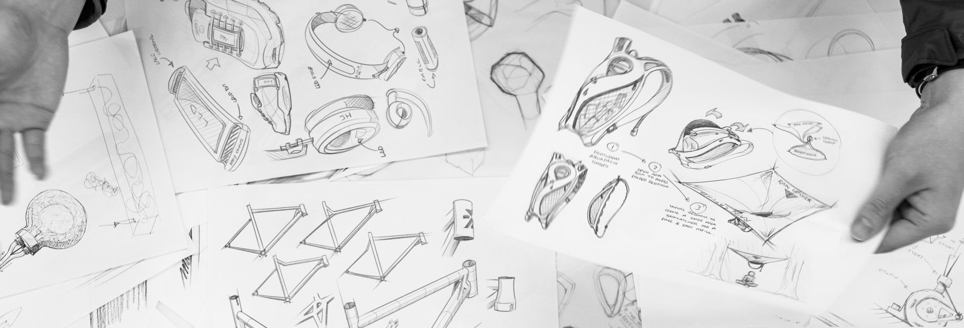Hands leafing through pages of product design sketches
